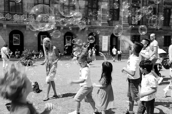 Kids playing with soap bubbles on a square in Amsterdam photographed by Astrid Julen.