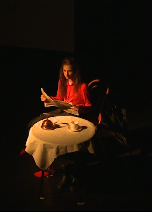 Astrid Julen reading the newspaper at a table in her choreography T-Raum.